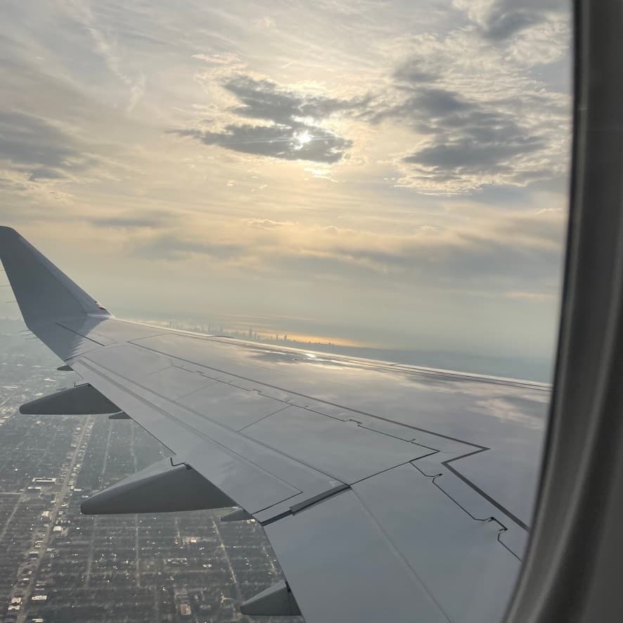 A picture of a plane window with a view of the sky