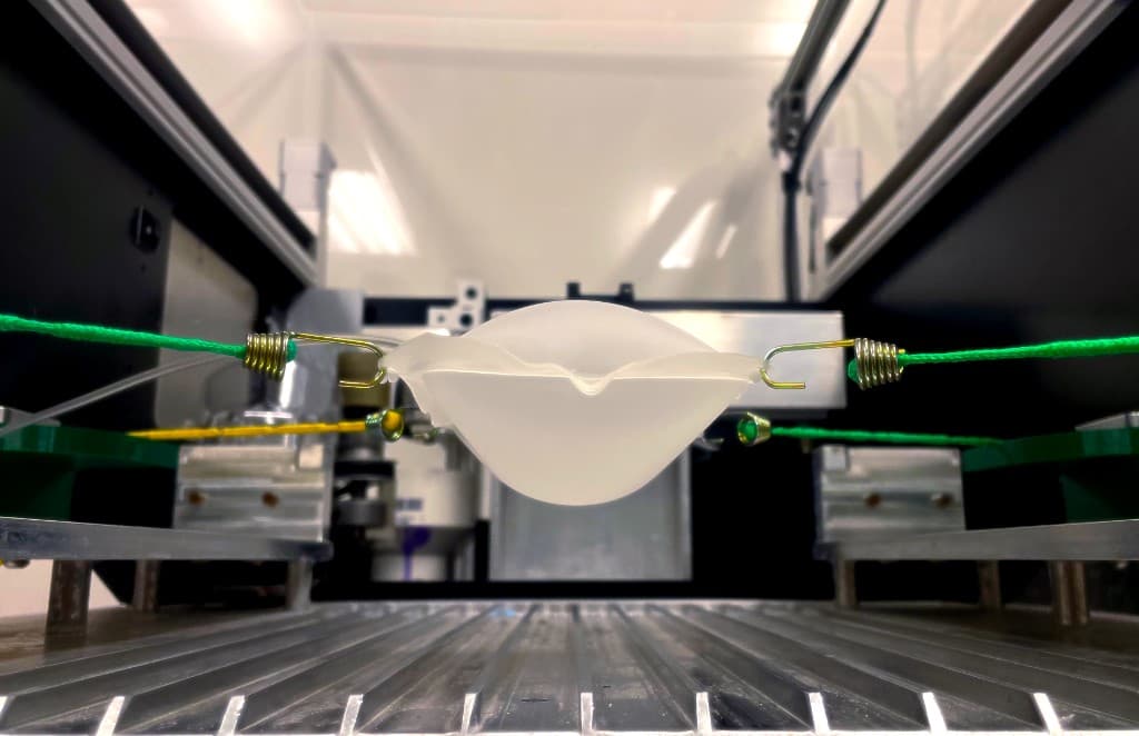 A soft robotics setup stretching a balloon-like actuator between two hooks